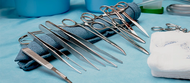 A carefully arranged selection of stainless-steel surgical instruments on a blue sterile drape